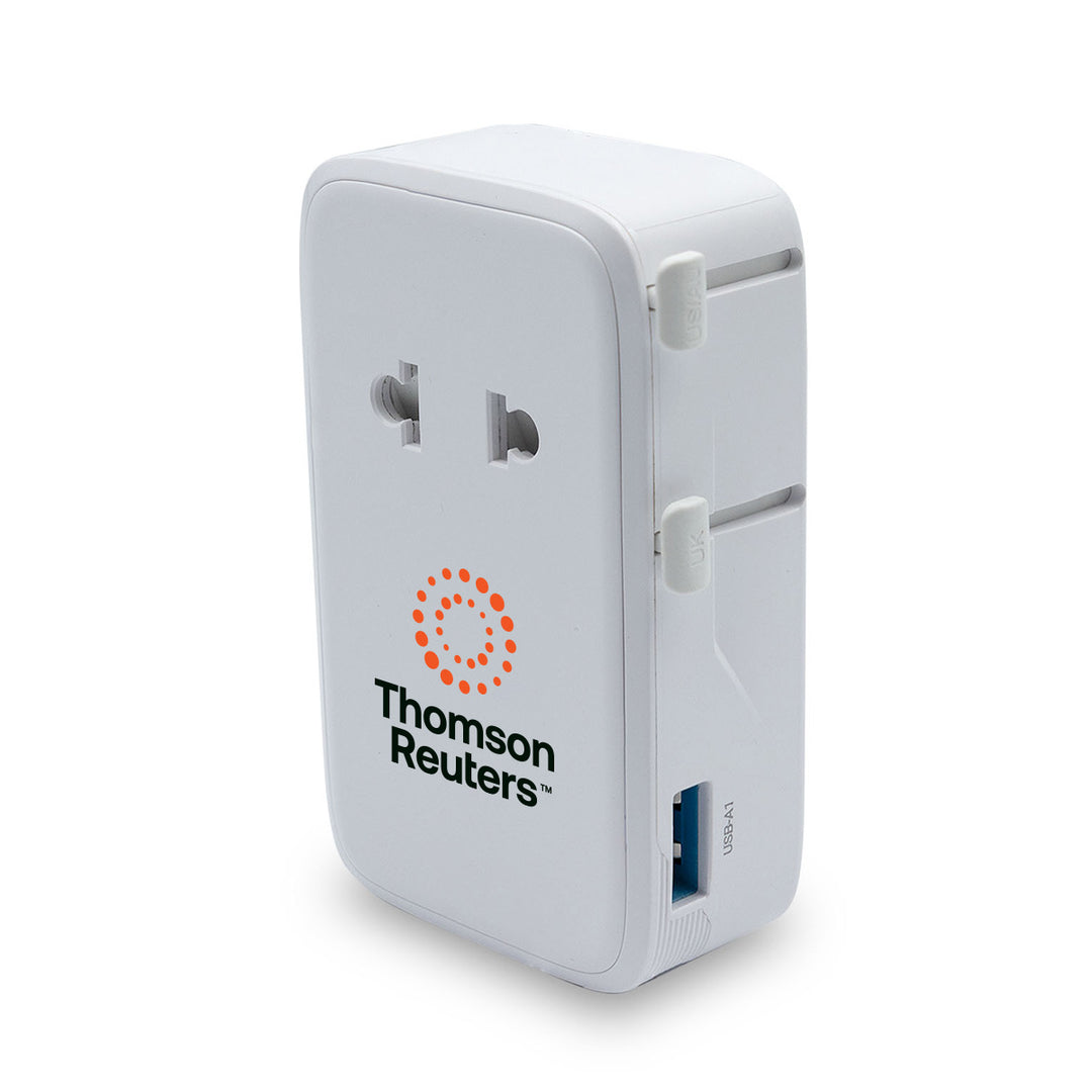 A white Thomson Reuters travel adapter with a US outlet on the front, a USB-C port on the side, and the Thomson Reuters logo printed in black and orange on the front face.